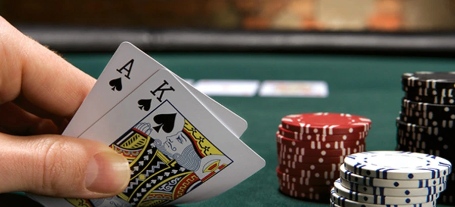 ace and king of spades folded up next to poker chips on game table